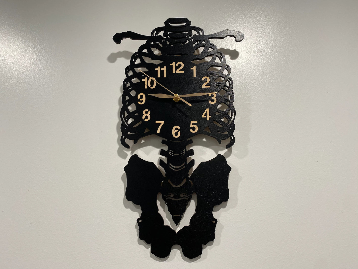 Laser-cut skeleton wall clock featuring ribcage, spine, and pelvis details