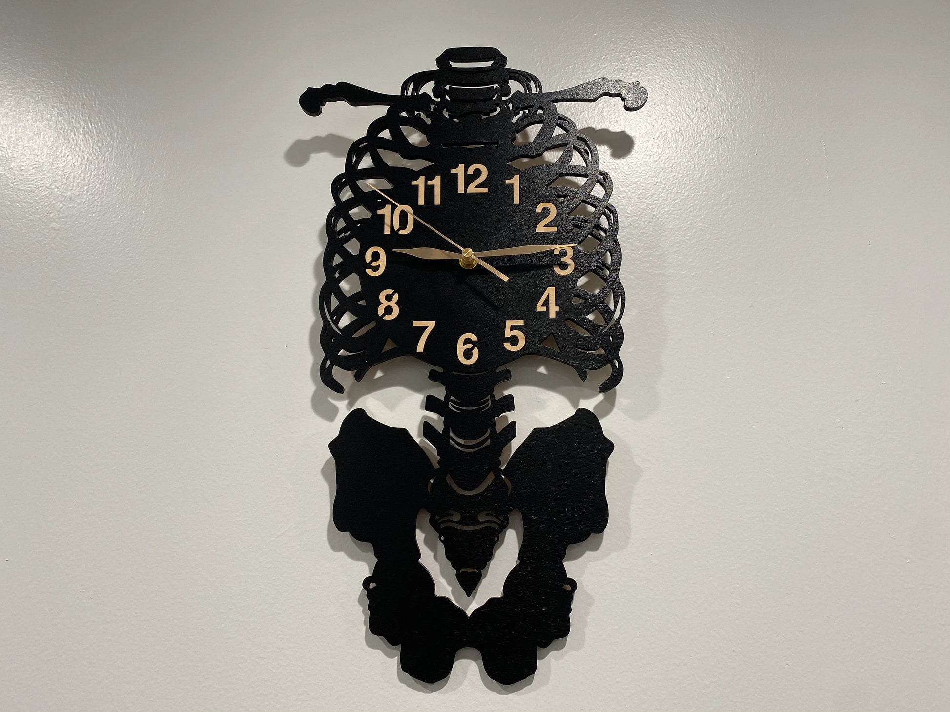 Laser-cut skeleton wall clock featuring ribcage, spine, and pelvis details