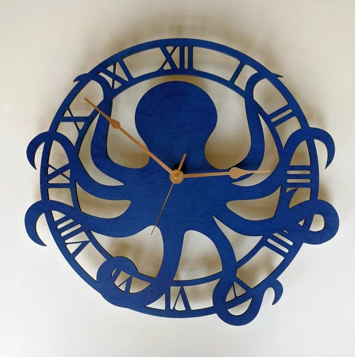Close-up of blue octopus clock showing wood grain and hands
