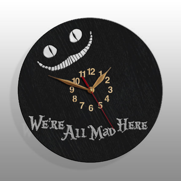 Close-up of black wall clock with Cheshire Cat's glowing smile and quote "We’re All Mad Here"
