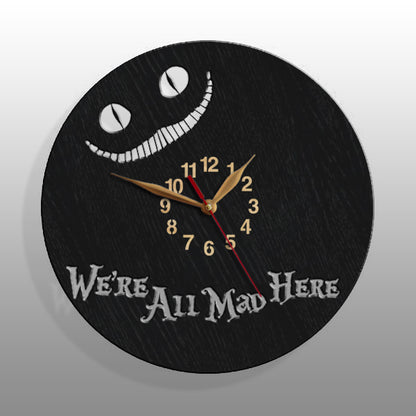 Close-up of black wall clock with Cheshire Cat's glowing smile and quote "We’re All Mad Here"