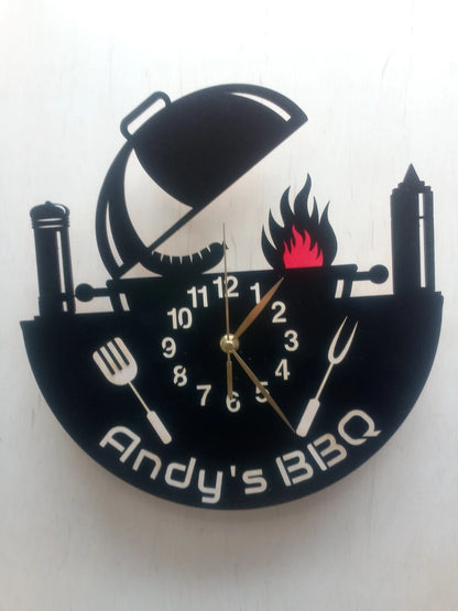 Personalized BBQ grill wall clock with cooking tools and flame design – custom name example “Andy’s BBQ”