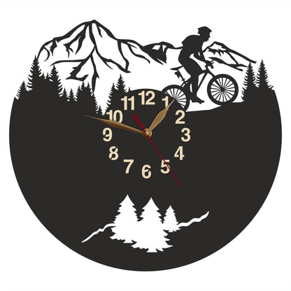 Wall clock with male cyclist silhouette riding through forest and mountains