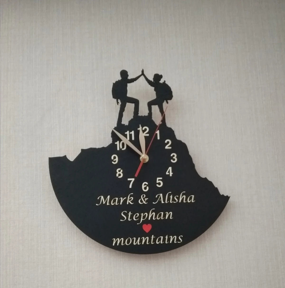 Wall clock featuring a hiking couple with custom names and a red heart symbol – ideal for anniversary or wedding gift.