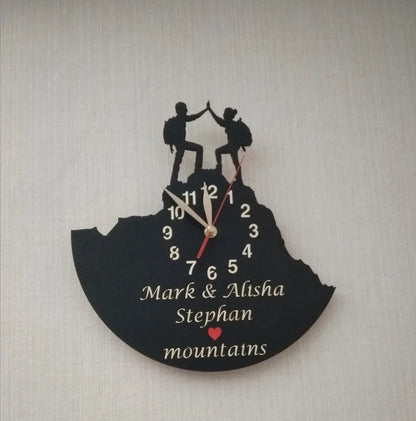 Wall clock featuring a hiking couple with custom names and a red heart symbol – ideal for anniversary or wedding gift.