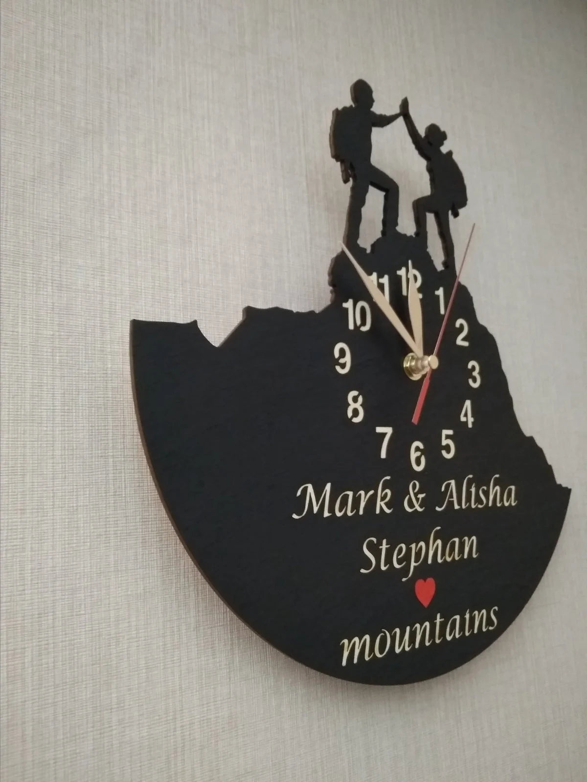 Wall clock with man and woman hikers giving a high-five on a mountain peak – personalized name engraving.