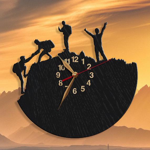 Wall clock silhouette featuring four climbers working together to reach the mountain summit.