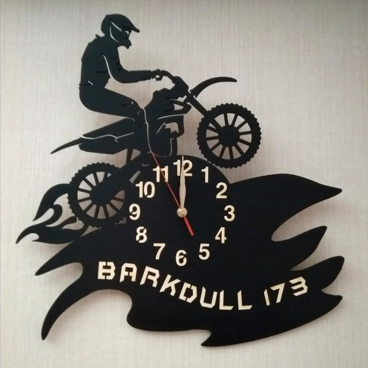 Wall clock featuring a motocross rider silhouette jumping over flames, personalized with a name