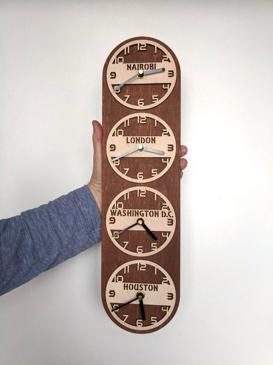 A vertical wall clock with multiple time zones displayed, customized with city names, mounted on a wall.