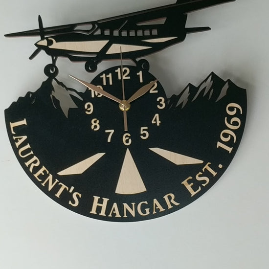 Handcrafted aviation wall clock with airplane above mountain peaks, perfect for pilots and travelers.