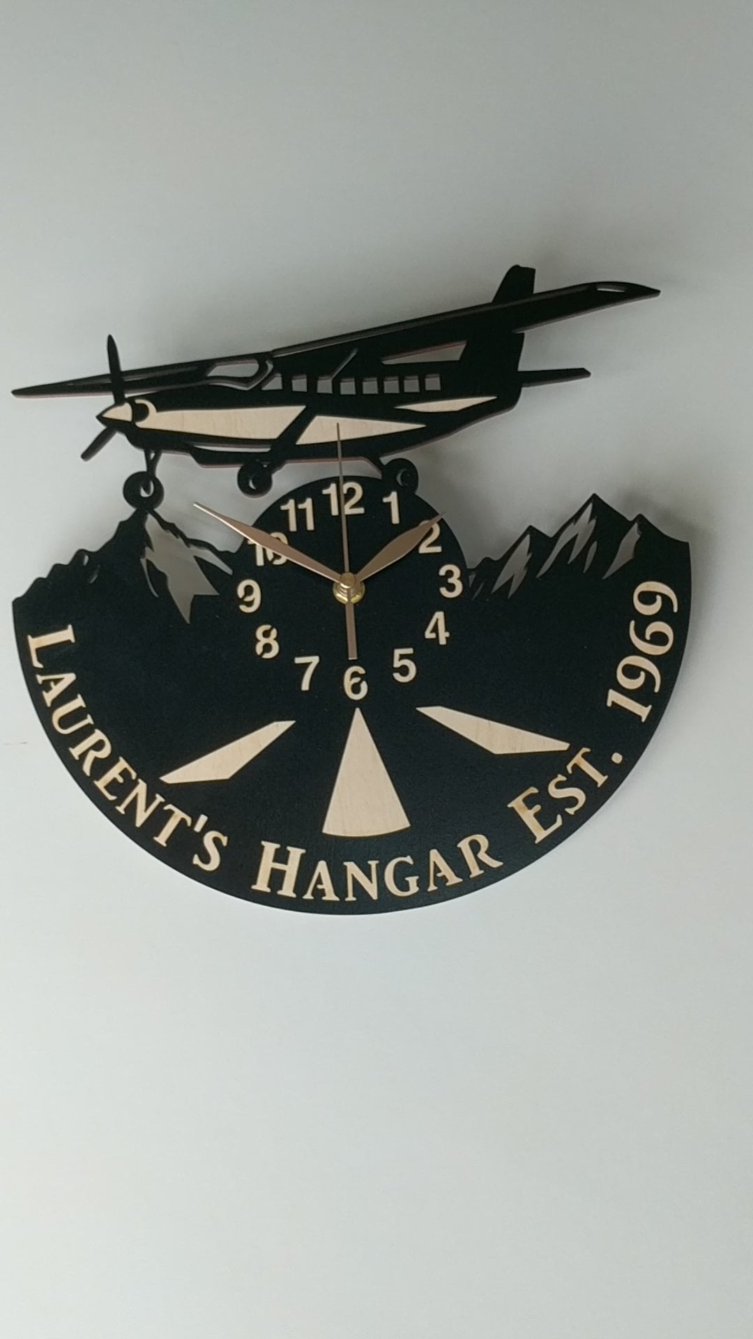 Handcrafted aviation wall clock with airplane above mountain peaks, perfect for pilots and travelers.