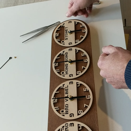 Video showing handmade wooden world time zone clocks with multiple dials, each labeled with different cities and time zones