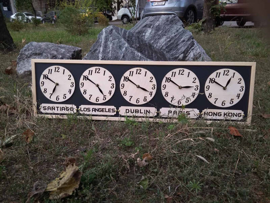 A multi-time zone wall clock with multiple white clock faces displayed in a row on a wooden board with a pine wood frame, set against a grassy background.